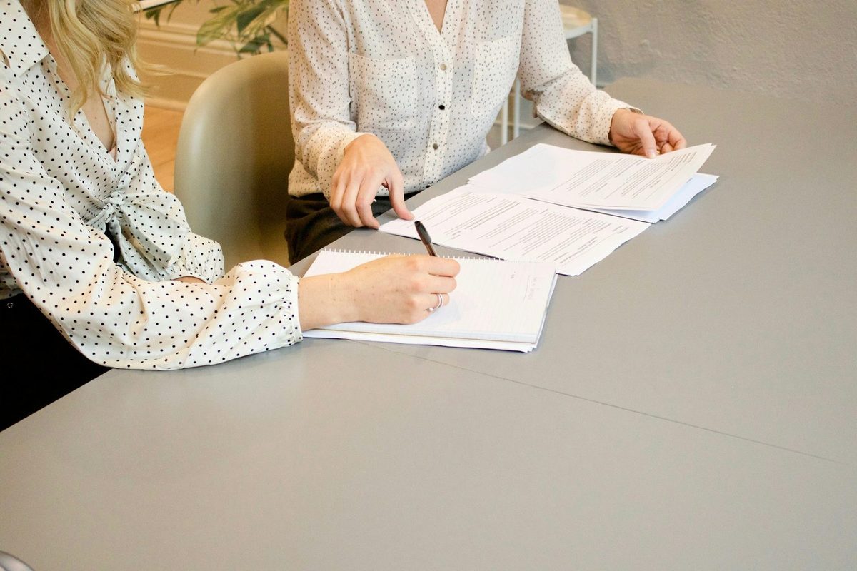 Two people at a table going through a stack of printed claims and taking notes